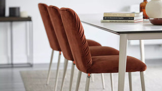 Sfeerbeeld van roestrode Mobitec Aura stoelen aan een witte tafel