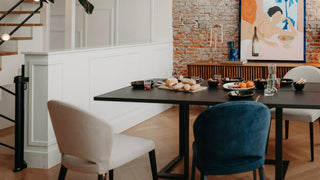 Sfeerbeeld van beige en petrolkleurige Mobitec Cuori stoelen aan een zwarte tafel voor een bakstenen muur