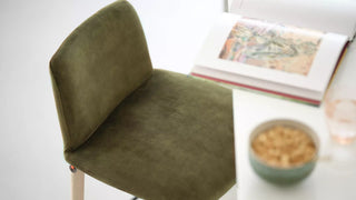 Detail van een groene velours Mobitec Rob kruk met boek en kom
