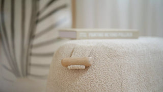 Detail of an ecru bouclé Mobitec Thalia pouf with wooden handle