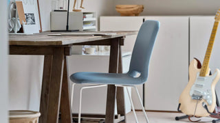 Sfeerbeeld van een blauwe Mobitec Pamp stoel aan een houten tafel met gitaar